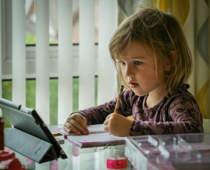 Little girl sitting infront of an ipad doing school
